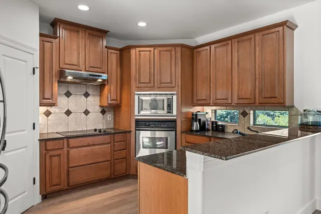 a kitchen with stainless steel appliances granite countertop a sink a stove and a refrigerator