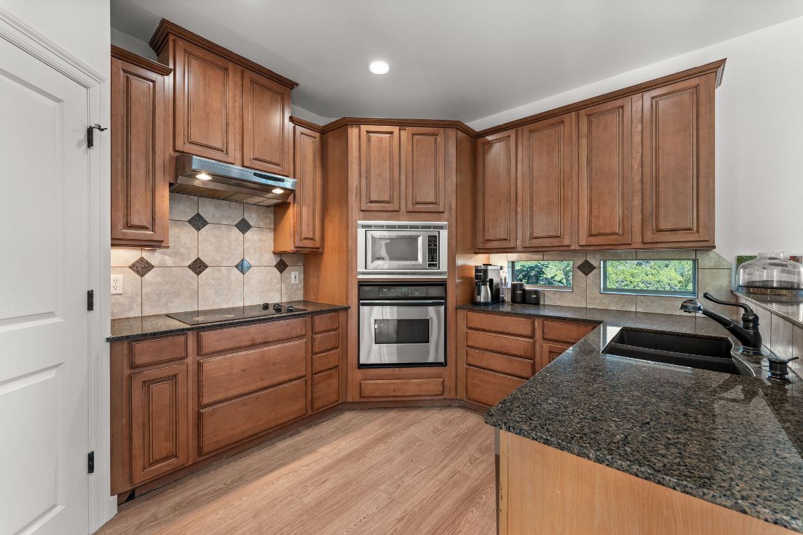 14000 Saskatchewan Drive Austin, TX 78734 - Photo 9 of 27 a kitchen with granite countertop wooden cabinets a microwave and stove