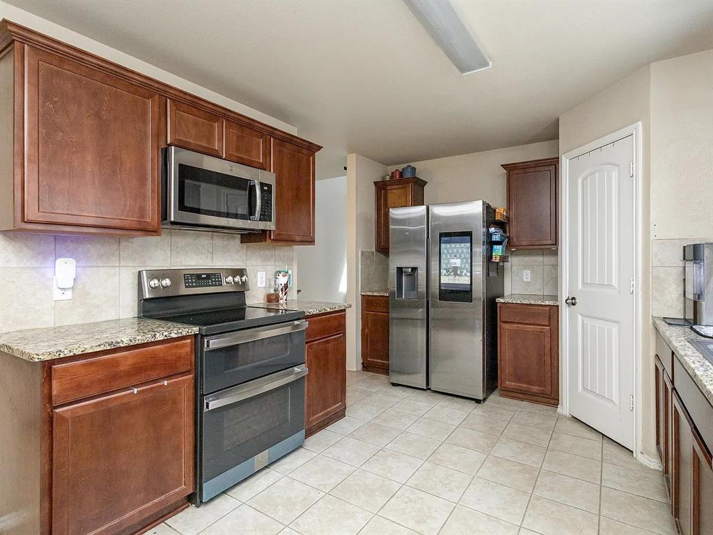 2320 Willard Way Forney, TX 75126 - Photo 6 of 26 a kitchen with stainless steel appliances granite countertop a stove a refrigerator and a microwave