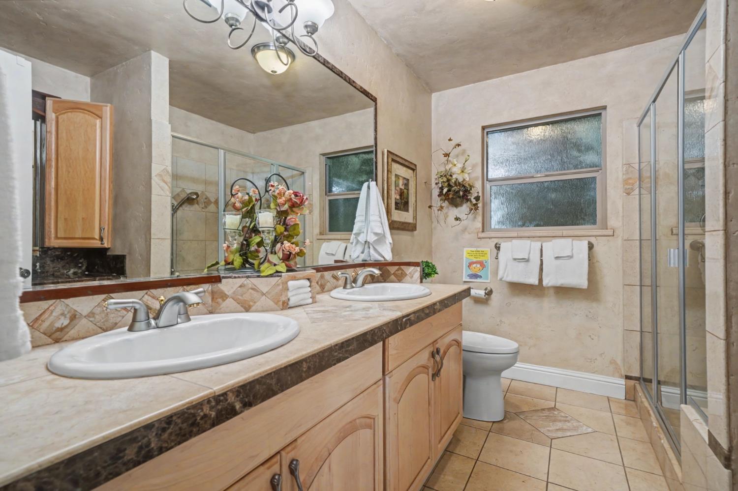 450 Lakeview Road Copperopolis, CA 95228 - Photo 40 of 93 a bathroom with a granite countertop sink a toilet a mirror and shower