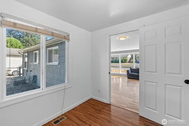 a view of a room with a large window and wooden floor