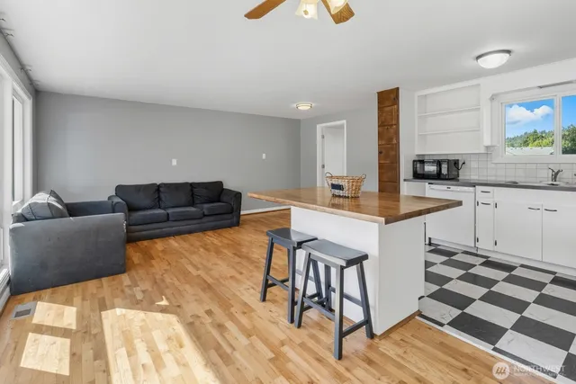 a living room with stainless steel appliances kitchen island granite countertop a sink and a granite counter tops