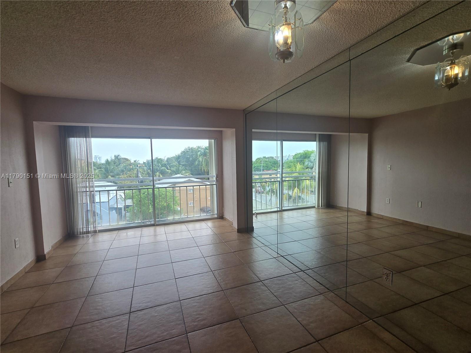 a view of an empty room with a floor to ceiling window and chandelier