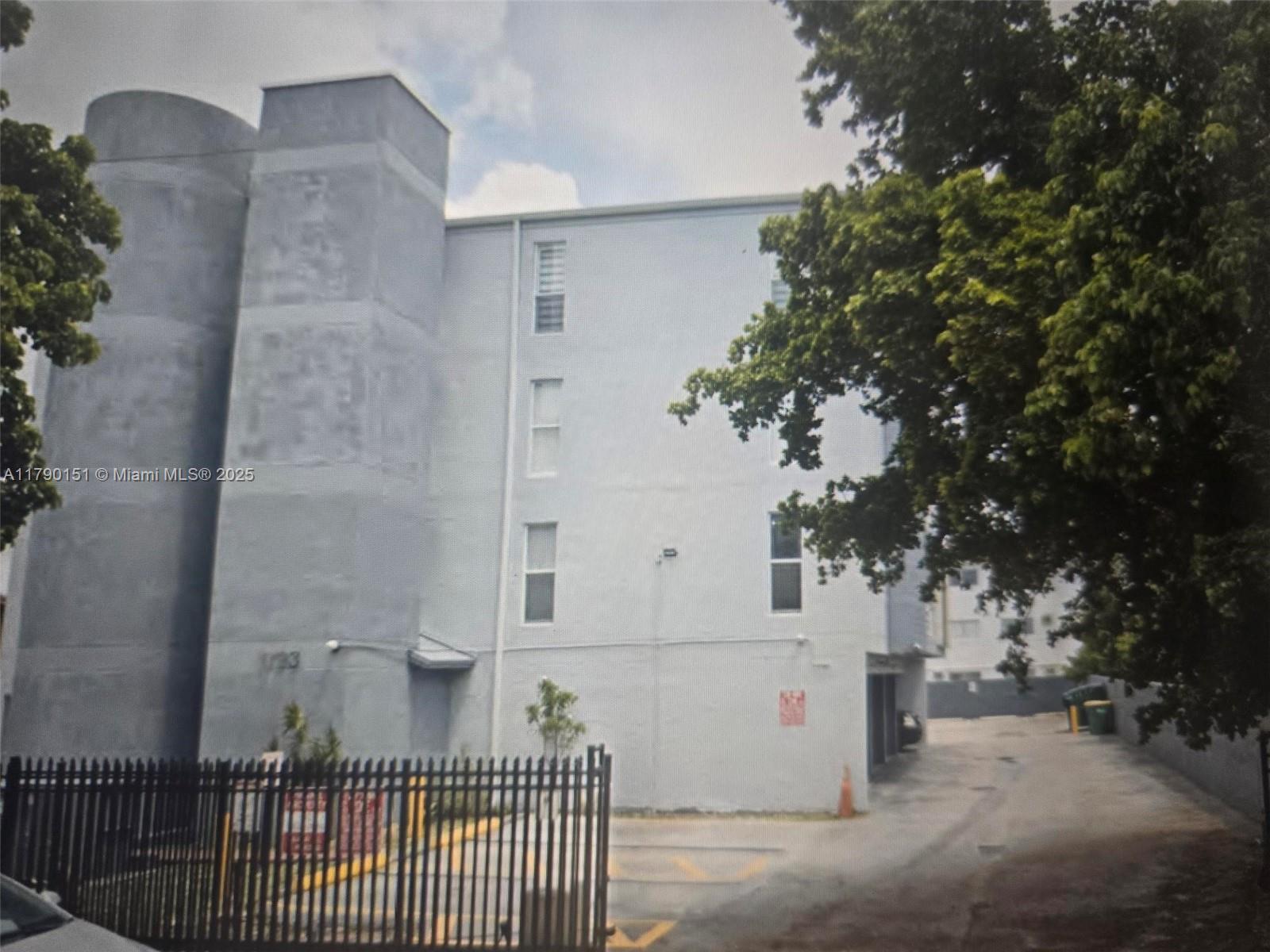 1793 Southwest 5th Street, Unit 401 Miami, FL 33135 - Photo 12 of 12 a view of a brick house with a large tree and wooden fence