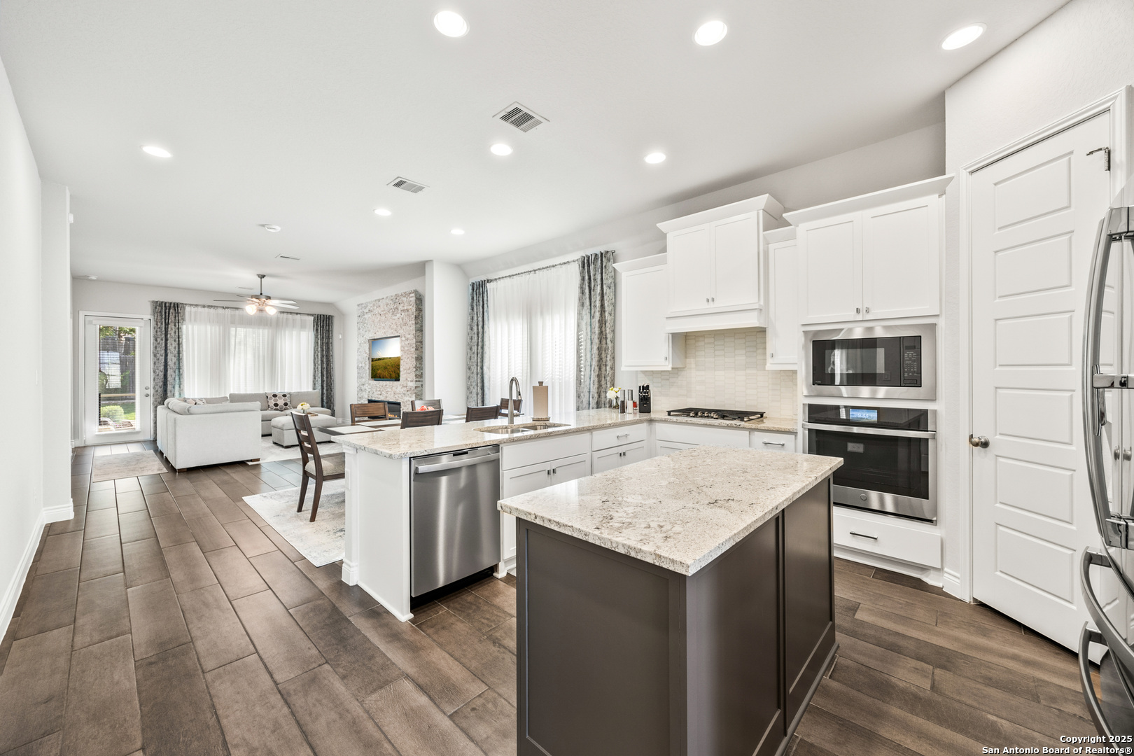 a large kitchen with a center island wooden floor and stainless steel appliances
