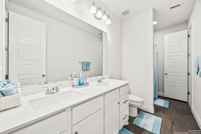 a bathroom with a double vanity sink mirror and toilet