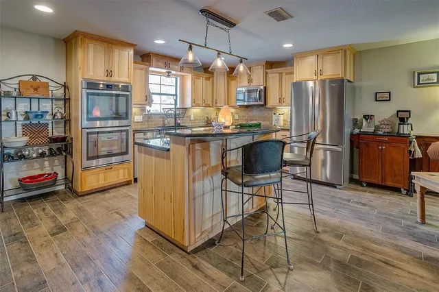 a kitchen with stainless steel appliances granite countertop a sink refrigerator and cabinets