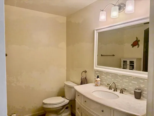a bathroom with a granite countertop sink a toilet and mirror
