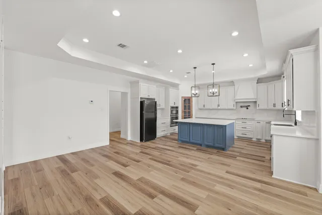 a large kitchen with stainless steel appliances a large counter top a stove and a refrigerator