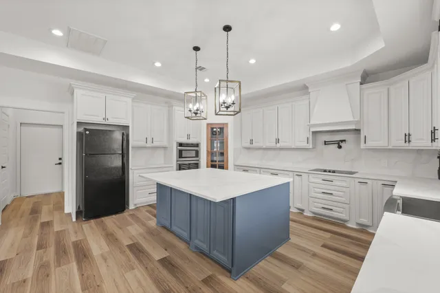 a kitchen with a refrigerator a sink dishwasher a stove and white cabinets with wooden floor