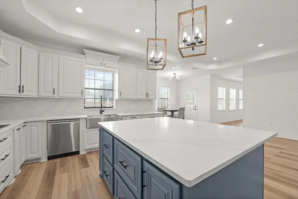 a large kitchen with kitchen island a stove a sink a center island and wooden floor