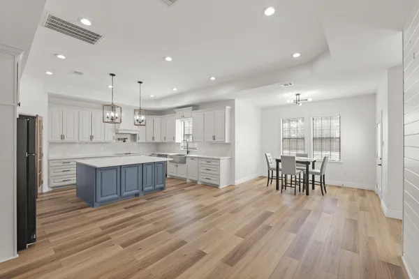 a kitchen with a table chairs wooden floors and view living room