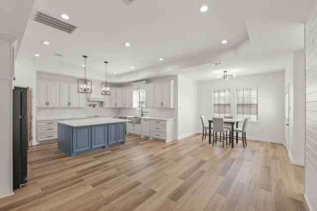 a kitchen with a table chairs wooden floors and view living room