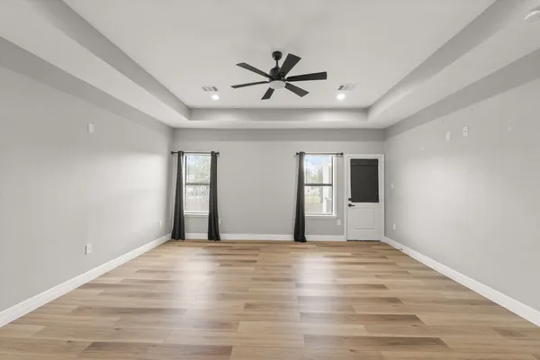 a view of an empty room with window and wooden floor