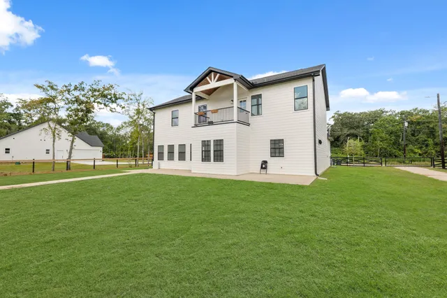 a view of a white house with a big yard and large trees