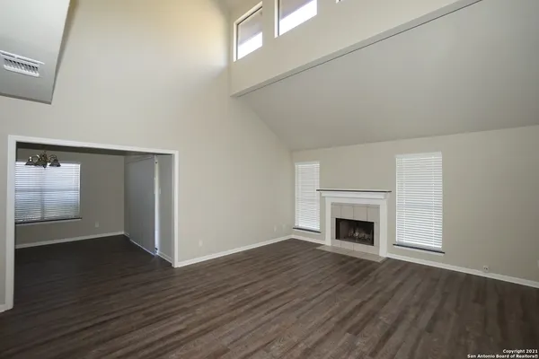 an empty room with wooden floor fireplace and windows