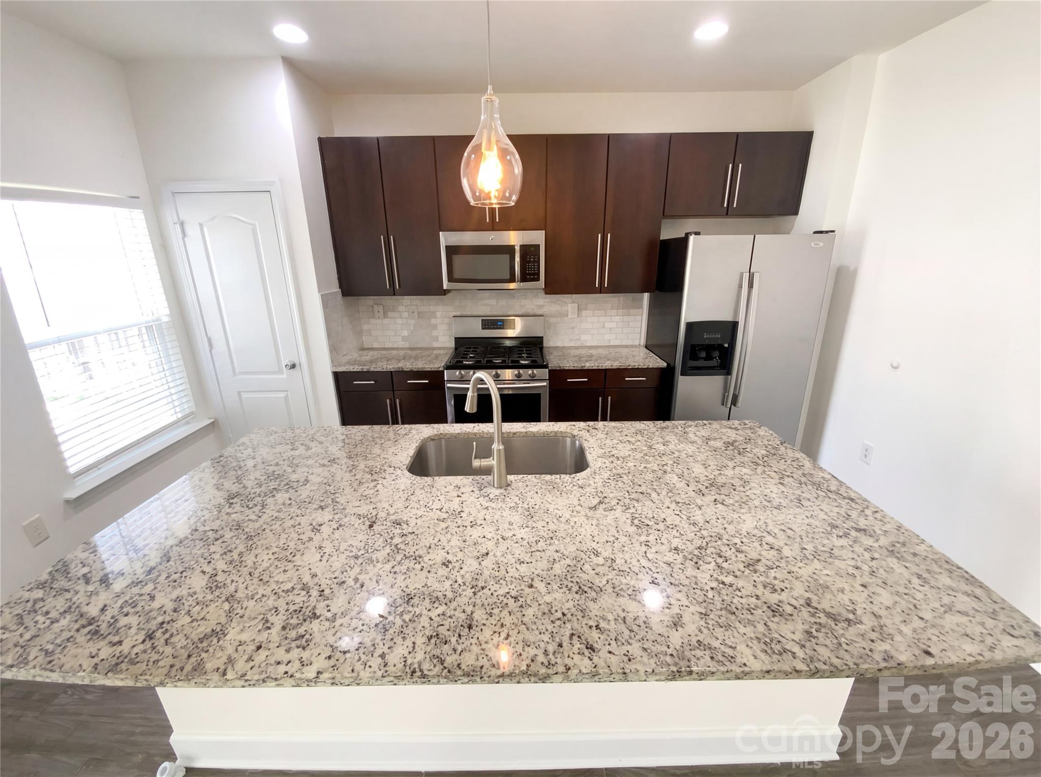 211 Waterlemon Way Monroe, NC 28110 - Photo 13 of 16 a kitchen with stainless steel appliances kitchen island granite countertop a sink refrigerator and microwave