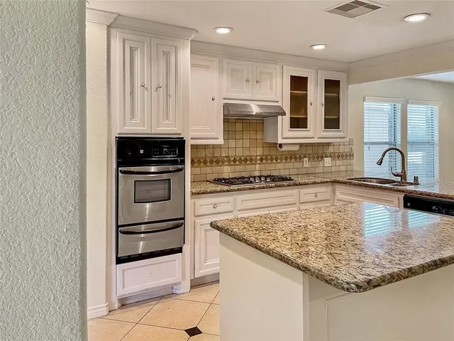 a kitchen with kitchen island granite countertop a sink stove and refrigerator
