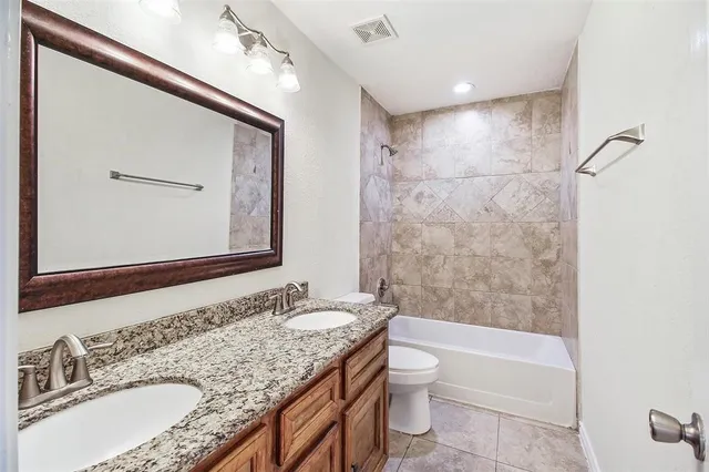 a bathroom with a granite countertop sink mirror toilet and bathtub