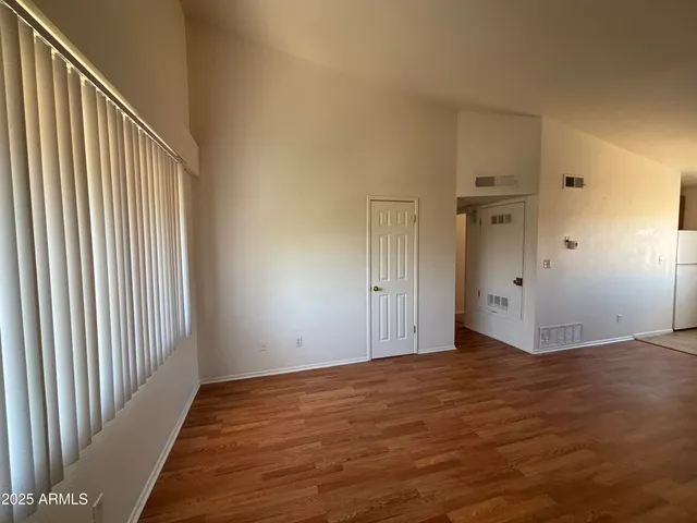 a view of kitchen and empty room with wooden floor