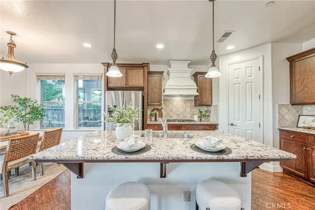 a kitchen with stainless steel appliances granite countertop a sink refrigerator and cabinets