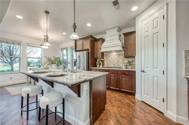a kitchen with kitchen island granite countertop a stove a sink a center island and wooden floor