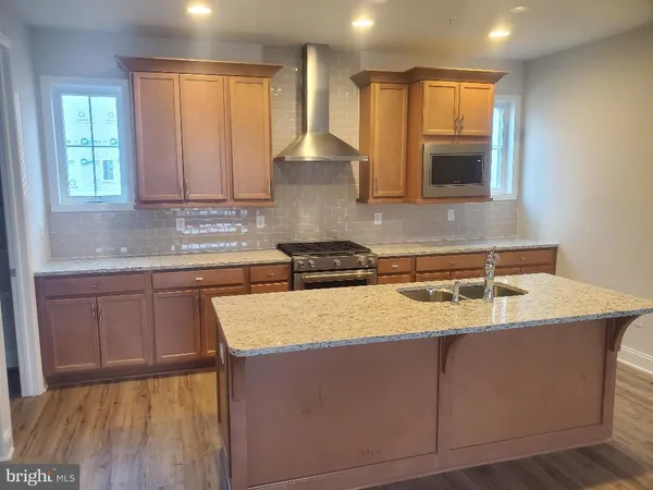a kitchen with kitchen island granite countertop a stove a sink and a microwave
