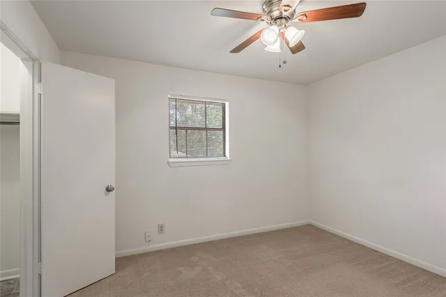 an empty room with a chandelier fan and windows