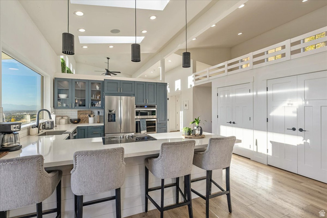 1800 Spring Oaks Drive Springville, UT 84663 - Photo 19 of 68 Kitchen with a peninsula, decorative light fixtures, stainless steel appliances, glass insert cabinets, and light wood-style floors
