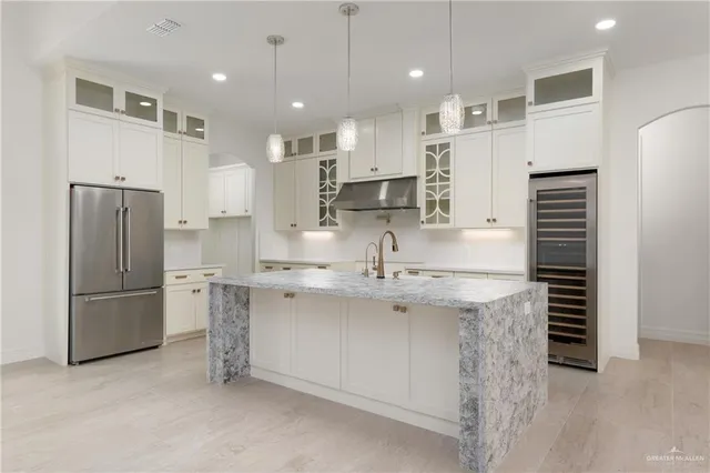 a kitchen with stainless steel appliances kitchen island granite countertop a refrigerator and a sink