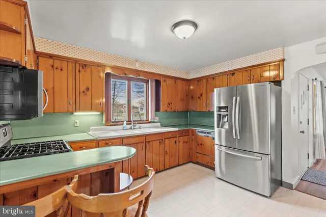 a kitchen with stainless steel appliances granite countertop a refrigerator a stove and a sink with wooden floor
