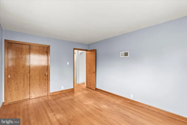 a view of an empty room with wooden floor and closet