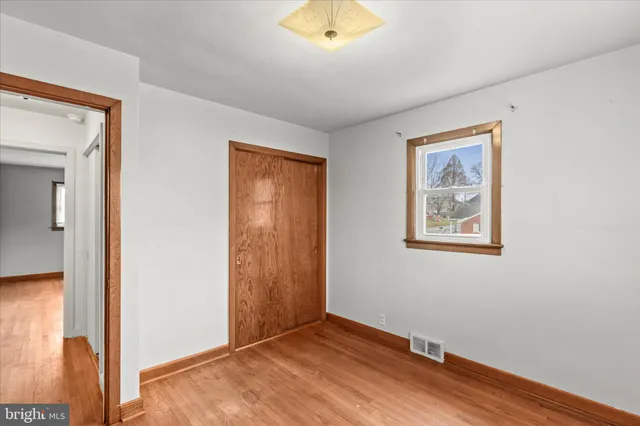 an empty room with wooden floor and closet