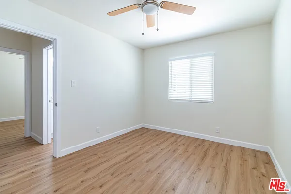 an empty room with wooden floor chandelier fan and windows