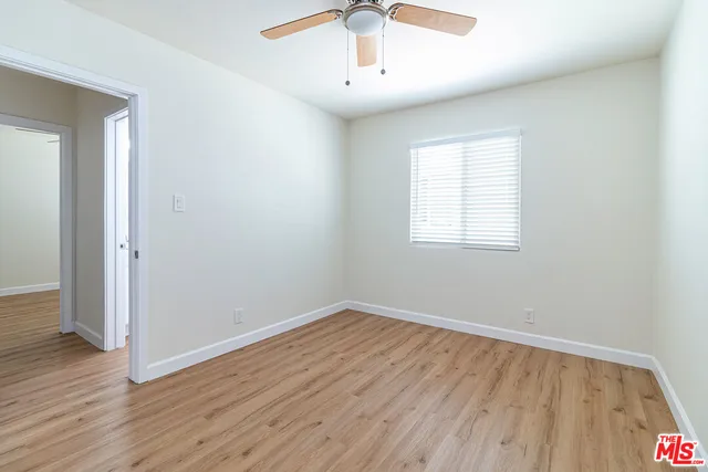 an empty room with wooden floor chandelier fan and windows