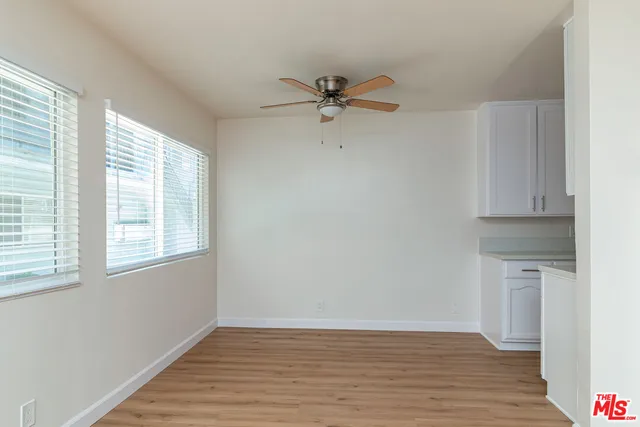 an empty room with wooden floor fan and windows