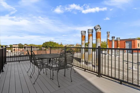 a view of a balcony with wooden chairs and floor to ceiling window