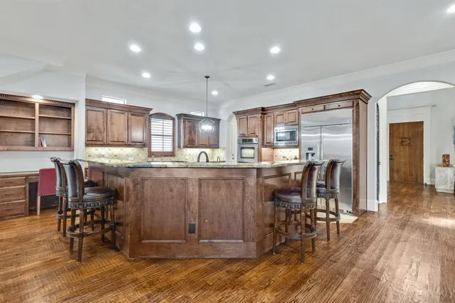 a kitchen with stainless steel appliances granite countertop dining table chairs refrigerator and cabinets