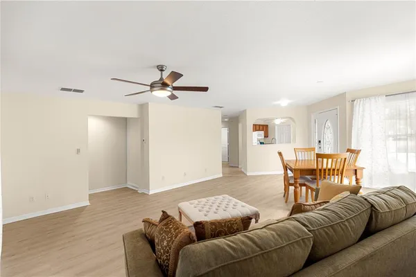 a living room with furniture and a dining table with wooden floor