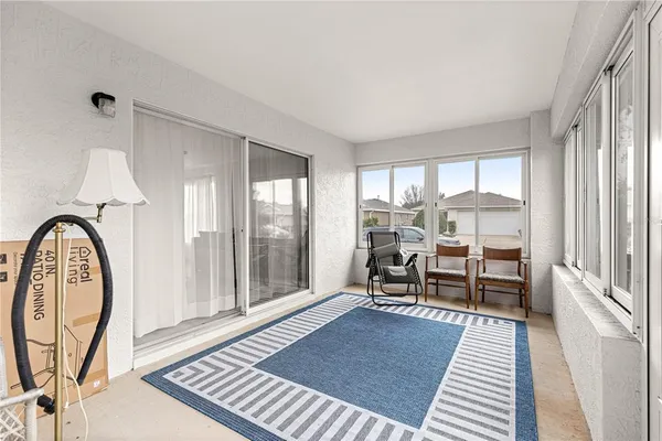 a living room with furniture a rug and a floor to ceiling window