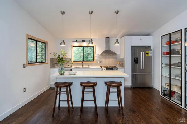 a kitchen with stainless steel appliances granite countertop a kitchen island wooden floors and white cabinets