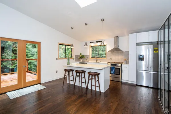 a kitchen with stainless steel appliances a dining table chairs stove refrigerator and cabinets