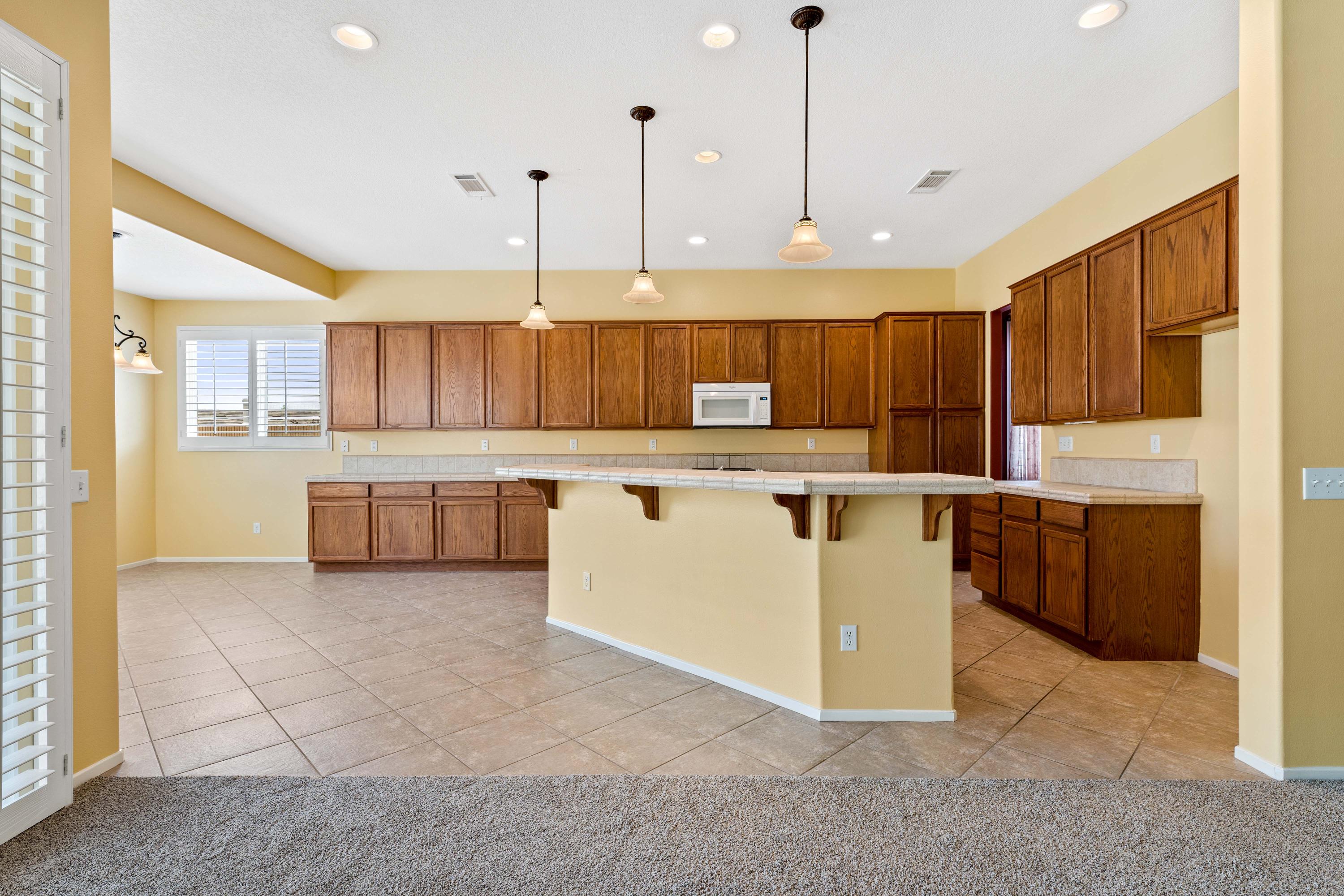 40451 Snake Lane Palmdale, CA 93551 - Photo 8 of 25 a kitchen with kitchen island a stove a sink a center island a counter top space and cabinets