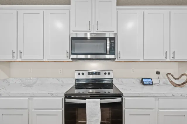a kitchen with granite countertop white cabinets and stainless steel appliances