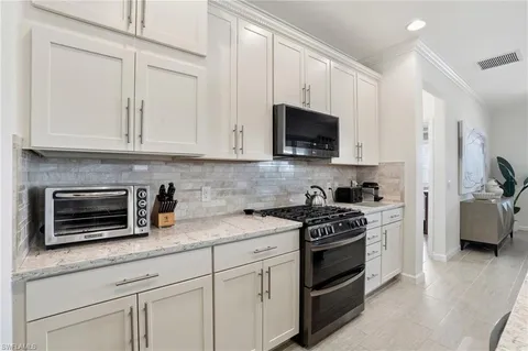 a kitchen with granite countertop white cabinets and stainless steel appliances