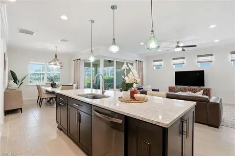 a kitchen with a sink a counter top space and living room view