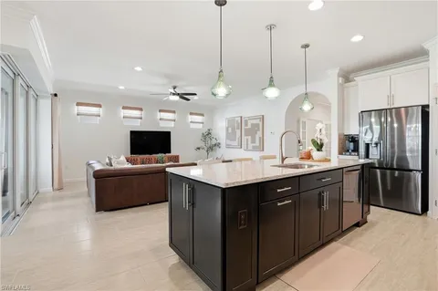 a kitchen with a refrigerator a sink and a flat screen tv