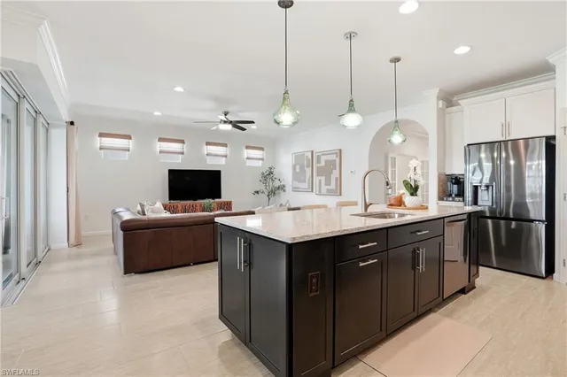 a kitchen with a refrigerator a sink and a flat screen tv