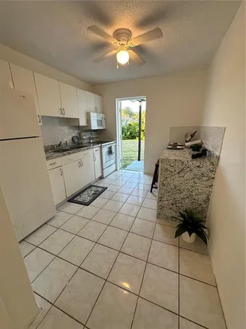 a kitchen with a refrigerator a stove top oven and white cabinets