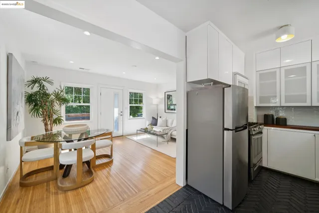 a kitchen with stainless steel appliances a refrigerator a stove a sink and white cabinets with wooden floor